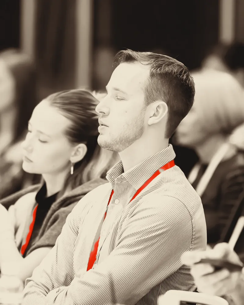 Two attendees listening closely, one with a red lanyard.